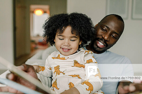 Glückliche Tochter liest mit ihrem Vater zu Hause ein Buch