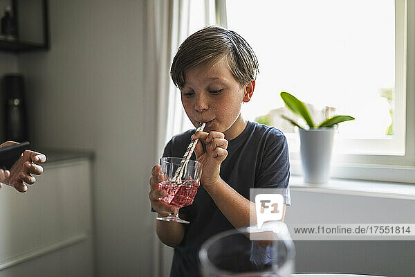 Boy drinking juice while standing in living room