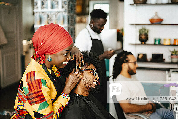 Eine Friseurin gibt einem männlichen Kunden im Friseursalon eine Kopfmassage