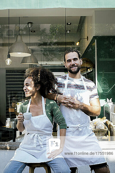 Lächelnde männliche und weibliche Besitzer vor einem Cafe