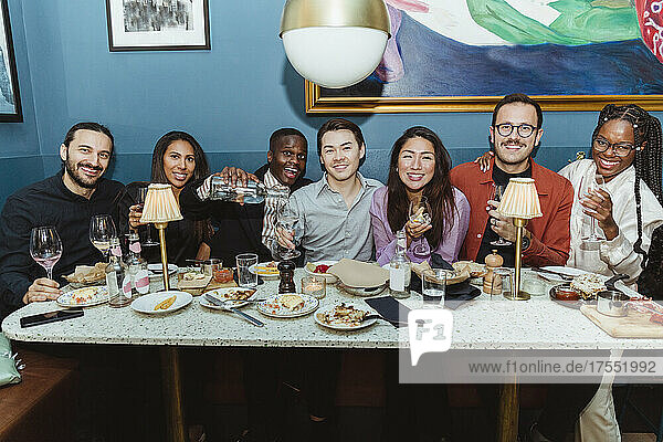 Porträt von lächelnden multirassischen Freunden mit Weingläsern in einem Restaurant