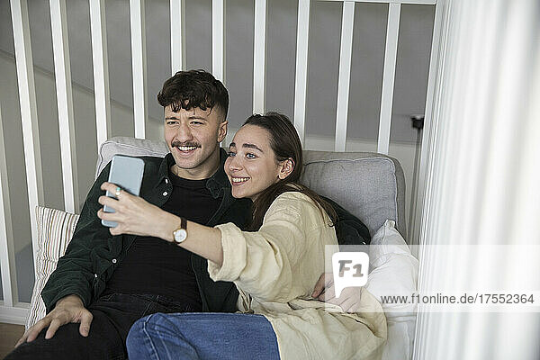 Happy young couple taking selfie on smart phone in bedroom
