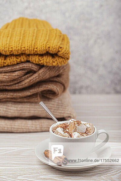 Hot chocolate with marshmallow and pile of warm knitted clothes