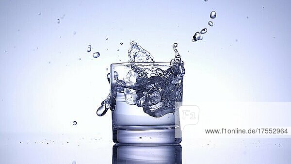 Eiswürfel fällt in ein Glas Wasser