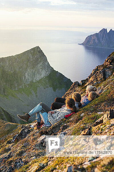 Junge skandinavische Frauen genießen den Sonnenuntergang und entspannen sich gemeinsam auf den Felsen  Insel Senja  Provinz Troms  Norwegen  Skandinavien  Europa