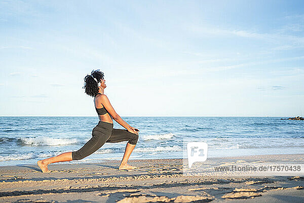 black woman practicing yoga by the sea