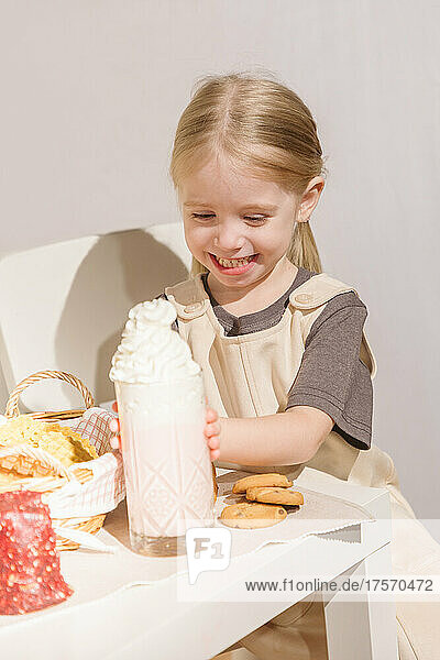 Cute little girl eating cookies with milkshake