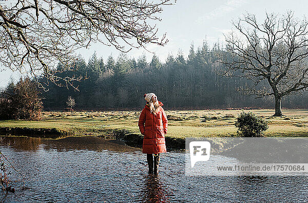 woman stood in a river enjoying the sunshine in winter