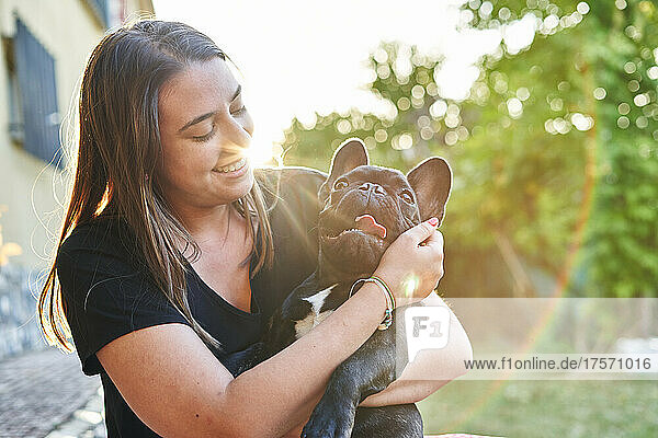 Young woman and her dog in the garden at sunset