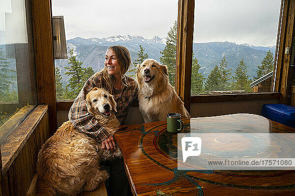Female with dogs having coffee in a mountain cabin