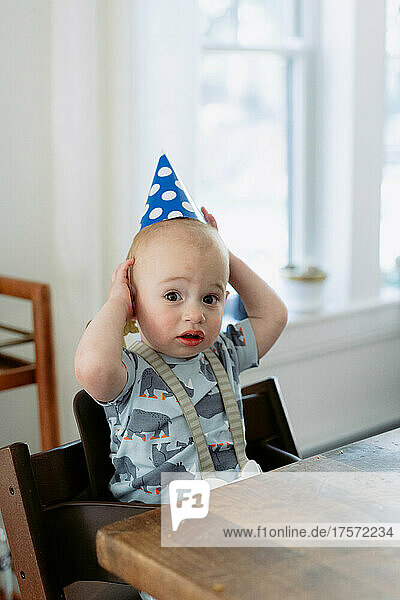 Confused one year old with party hat on his birthday