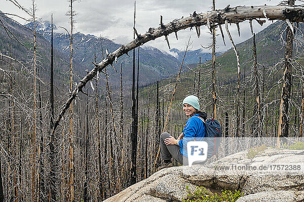 Female smiling sitting in a burned dead forest of trees
