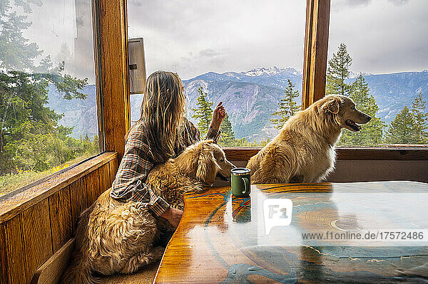 A female and their dogs sitting at the table in a mountain cabin