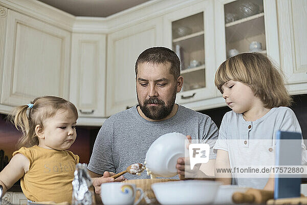 Father and two children prepare cookie dough