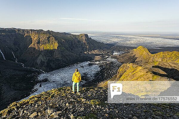 Hiker looks over spectacular landscape  cliffs and glacier Myrdalsjökull  Pakgil  Iceland  Europe