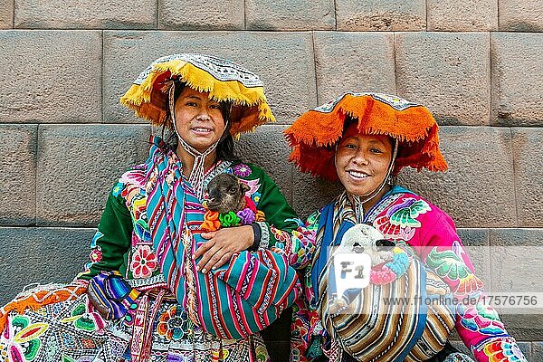 Two Inca woman in traditional traditional costume with lambs in front of an Inca wall  Cusco  Peru  South America