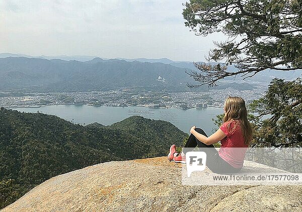 Junge Frau sitzt auf einem Stein  Blick in die Ferne  Komagabayashi Peak  Miyajima  Hiroshima  Japan  Asien