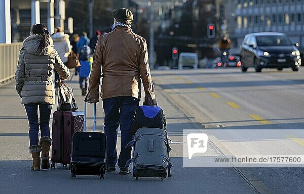 Passers-by with luggage on the pavement