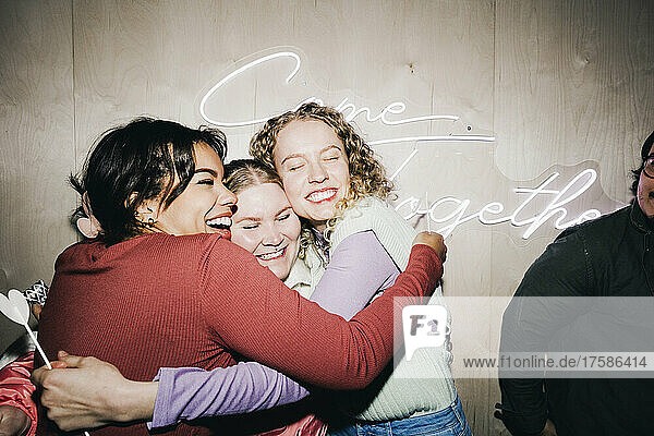 Glückliche multirassische Freundinnen umarmen sich im Studentenwohnheim