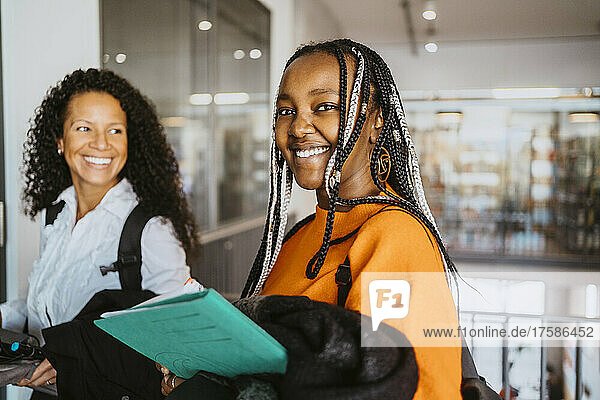 Portrait of smiling braided female student with friend in university