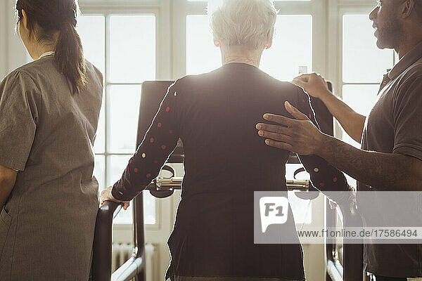 Männliche Pflegekraft unterstützt ältere Frau beim Training auf dem Laufband im Pflegeheim