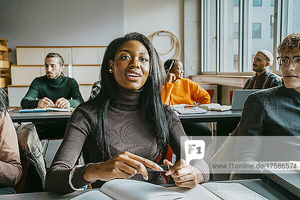 Junge Studentin sitzt mit Freunden im Klassenzimmer der Universität
