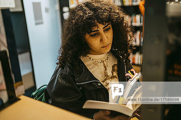Junge Studentin liest ein Buch in der Hochschulbibliothek
