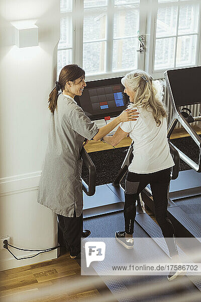 Krankenschwester unterstützt ältere Frau beim Training auf dem Laufband im Pflegeheim