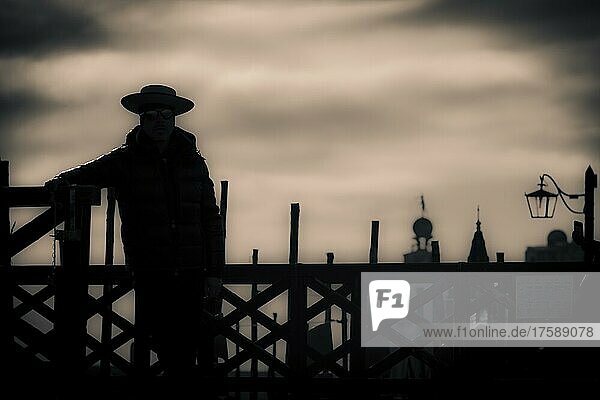 Gloomy atmosphere  gondoliers standing at a fence as silhouette against the light  Venice  Veneto  Italy  Europe