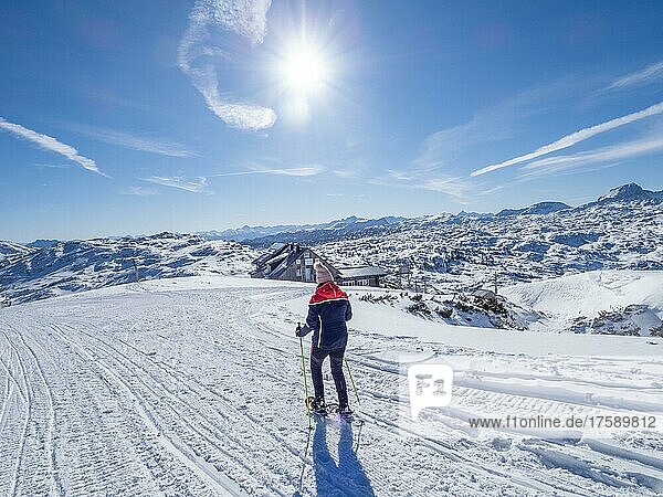 Schneeschuhwanderin in Winterlandschaft im Hochgebirge  hinten Krippenstein Lodge und verschneite Alpengipfel  Krippenstein  Salzkammergut  Oberösterreich  Österreich  Europa