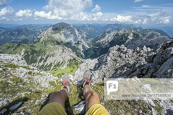 Berglandschaft  Wanderer lässt Beine baumeln  Wanderschuhe und Ausblick von der Lamsenspitze auf Berge und das Gramaital  Karwendelgebirge  Tirol  Österreich  Europa