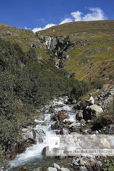 Wanderer sitzt am Gebirgsbach mit Wasserfall im Rofental  Vent  Venter Tal  Gemeinde Sölden  Ötztaler Alpen  Tirol  Österreich  Europa