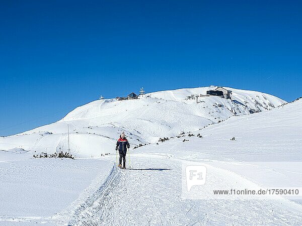 Blauer Himmel über Schneeschuhwanderin in Winterlandschaft  verschneite Berggipfel  Aussicht zum Krippenstein  Bergstation und Krippenstein Lodge  Salzkammergut  Oberösterreich  Österreich  Europa