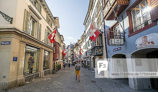 Tourist in der Augustinergasse  Straße mit historischen Häusern und Schweizer Flaggen in der Altstadt  Zürich  Schweiz  Europa