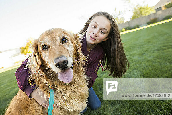 Girl (12-13) with Golden Retriever on lawn
