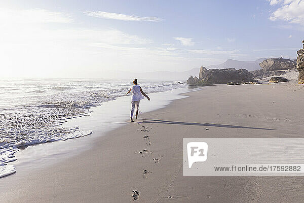 South Africa  Hermanus  Girl (16-17) walking on Sopiesklip beach in Walker Bay Nature Reserve