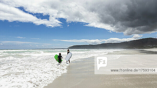 South Africa  Hermanus  Girl (16-17) and boy (8-9) with body boards on Grotto Beach