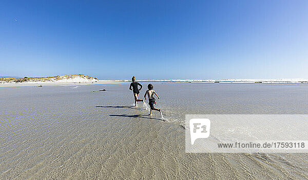 South Africa  Hermanus  Girl (16-17) and boy (8-9) running on Grotto Beach