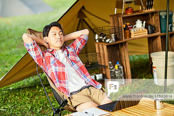 Japanese Man Teleworking At Campsite