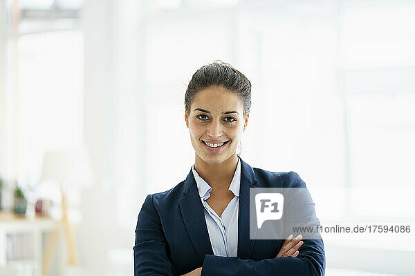 Smiling businesswoman with arms crossed at office