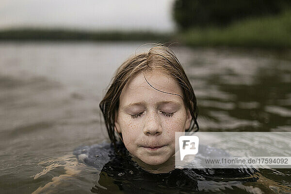 Mädchen mit geschlossenen Augen schwimmt im See