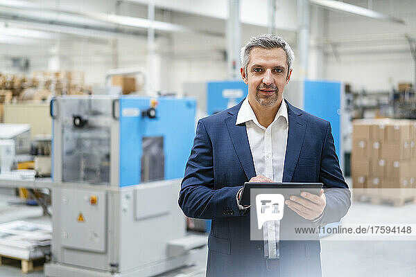 Businessman with tablet PC standing in factory