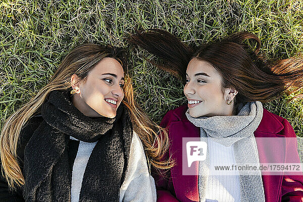 Lächelnde Frauen  die einander im Gras anschauen