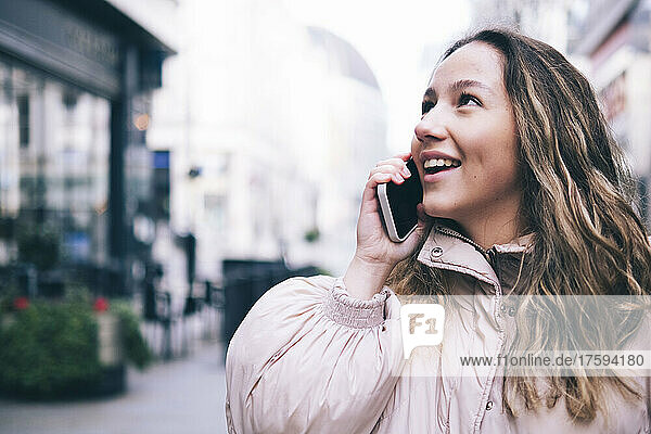 Lächelnde Frau  die auf der Straße mit ihrem Smartphone spricht