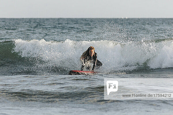 Determined woman surfing in front of wave in sea  Gran Canaria  Canary Islands