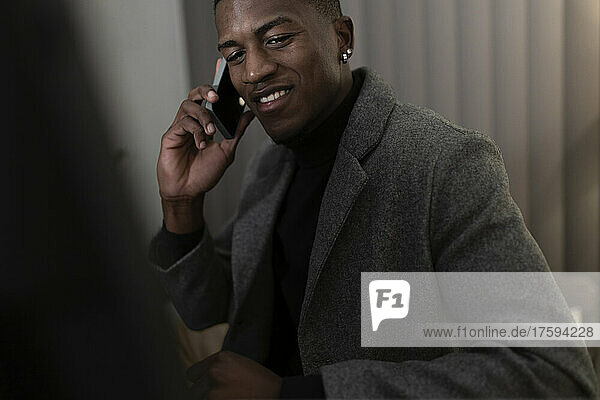 Smiling businessman talking on mobile phone at home office working late night
