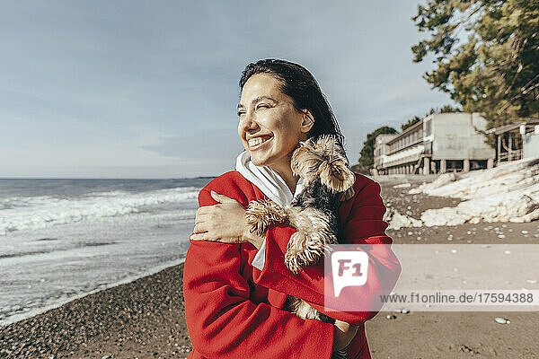 Happy woman with Yorkshire terrier at beach