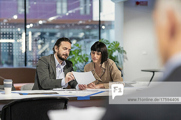 Manager discussing with colleague over paper document at office