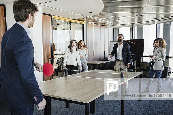 Business colleagues playing table tennis in coworking office