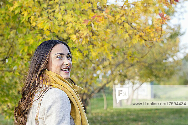 Happy woman with yellow scarf in autumn park